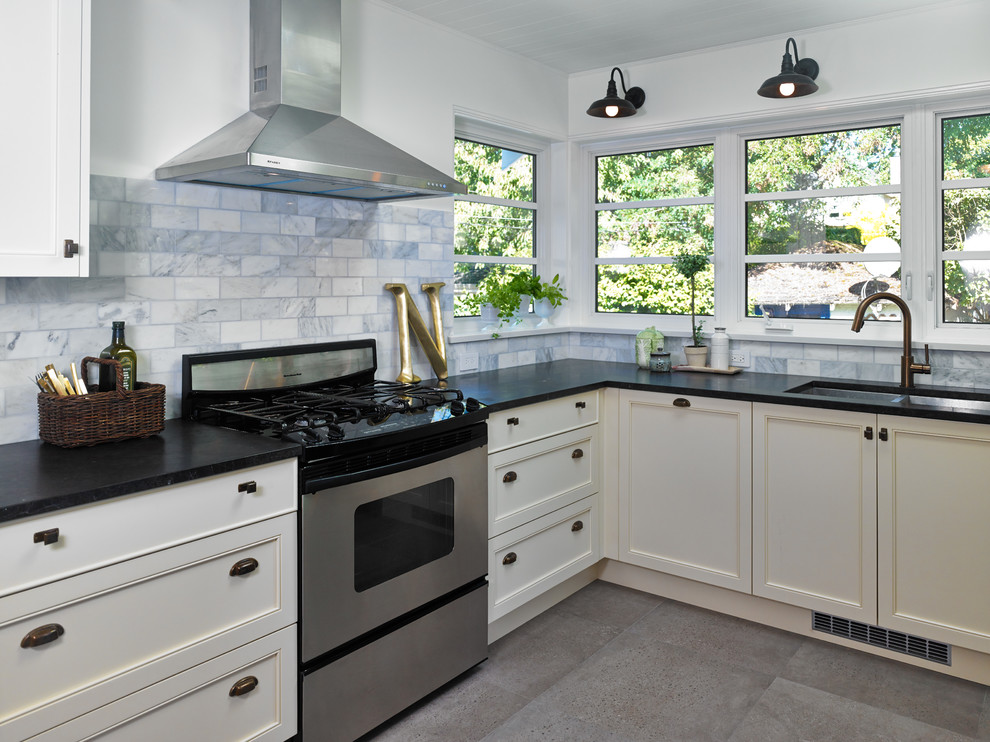 Photo of a transitional u-shaped kitchen in Vancouver with an undermount sink, recessed-panel cabinets, beige cabinets, white splashback and stainless steel appliances.