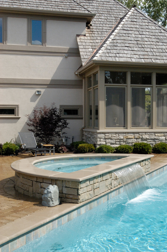 Inspiration for a mid-sized traditional backyard rectangular lap pool in Chicago with concrete pavers and a hot tub.
