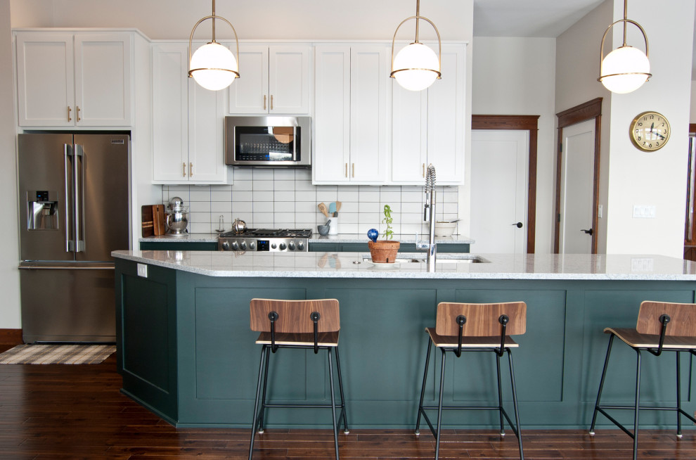 Photo of a transitional galley kitchen in Other with an undermount sink, shaker cabinets, green cabinets, white splashback, stainless steel appliances, dark hardwood floors, with island, brown floor and white benchtop.