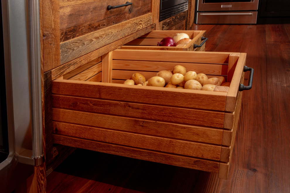 Inspiration for a mid-sized rustic l-shaped medium tone wood floor and brown floor eat-in kitchen remodel with a farmhouse sink, shaker cabinets, black cabinets, quartz countertops, black backsplash, stainless steel appliances, an island and black countertops
