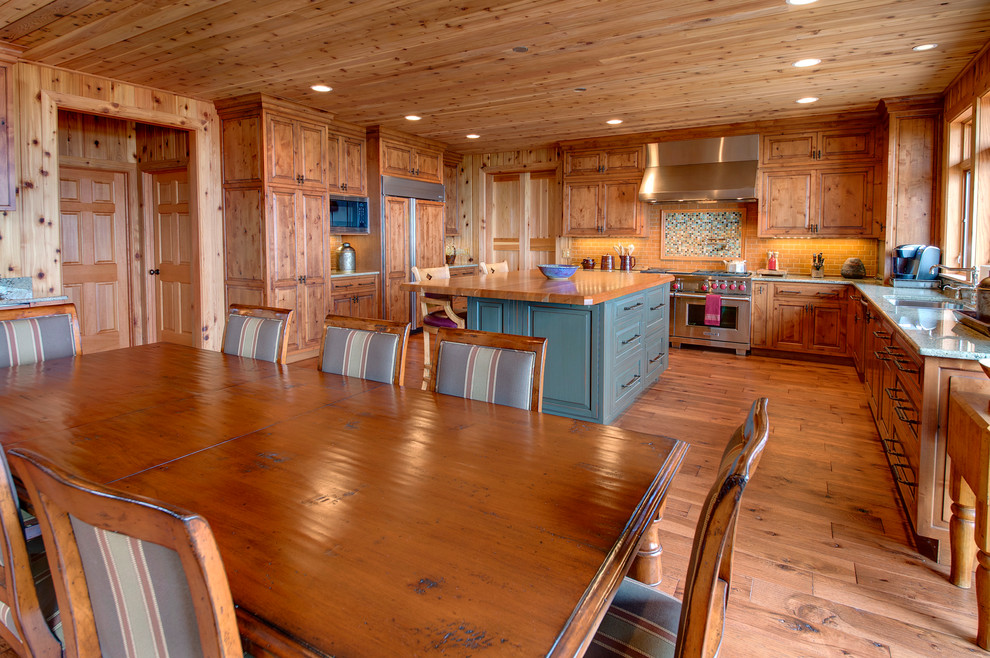 Eat-in kitchen - mid-sized rustic u-shaped light wood floor and brown floor eat-in kitchen idea with an undermount sink, raised-panel cabinets, light wood cabinets, granite countertops, yellow backsplash, ceramic backsplash, stainless steel appliances and an island