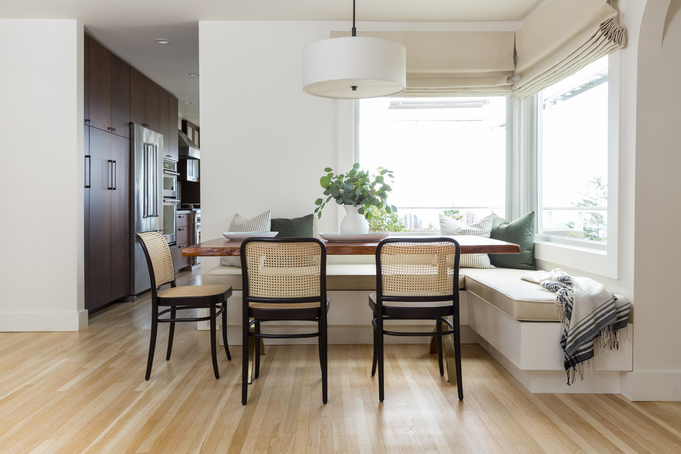 This is an example of a transitional dining room in San Francisco with white walls, light hardwood floors and beige floor.