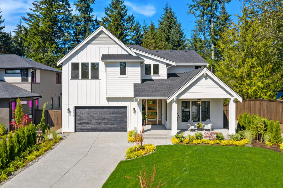 Large country two-storey white house exterior in Seattle with wood siding, a gable roof, a shingle roof, a grey roof and board and batten siding.