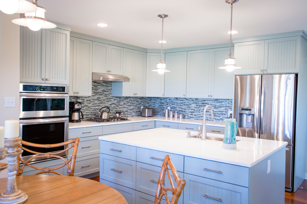 Design ideas for a mid-sized traditional l-shaped eat-in kitchen in Atlanta with an undermount sink, louvered cabinets, blue cabinets, quartzite benchtops, blue splashback, glass tile splashback, stainless steel appliances, medium hardwood floors and with island.