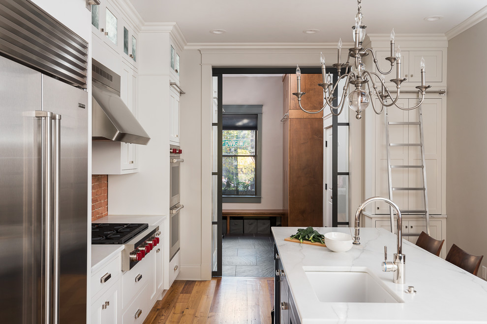 Eat-in kitchen - mid-sized mid-century modern l-shaped medium tone wood floor eat-in kitchen idea in Boston with an undermount sink, shaker cabinets, white cabinets, marble countertops, red backsplash, stainless steel appliances and an island
