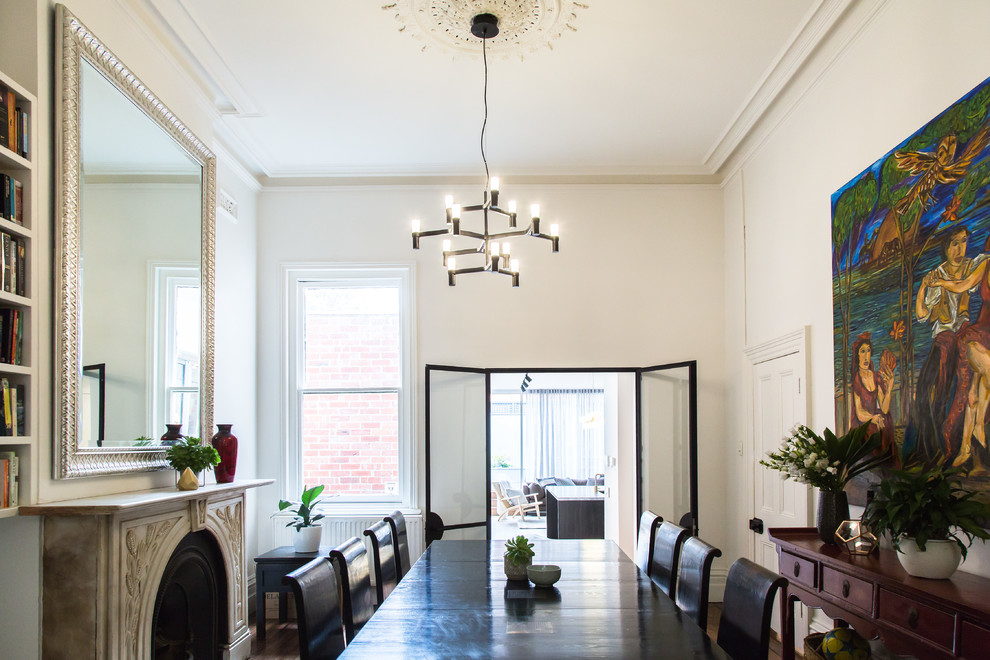 Inspiration for a mid-sized transitional separate dining room in Melbourne with white walls, medium hardwood floors, a stone fireplace surround and brown floor.