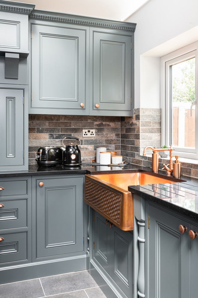 Medium sized classic l-shaped kitchen/diner in Dorset with beaded cabinets, grey cabinets, quartz worktops, stone tiled splashback, an island and black worktops.