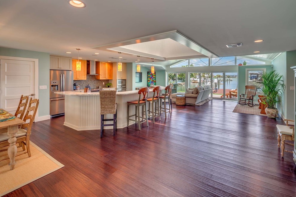 Mid-sized tropical u-shaped open plan kitchen in Tampa with a double-bowl sink, louvered cabinets, white cabinets, quartz benchtops, multi-coloured splashback, mosaic tile splashback, stainless steel appliances, dark hardwood floors, a peninsula and brown floor.