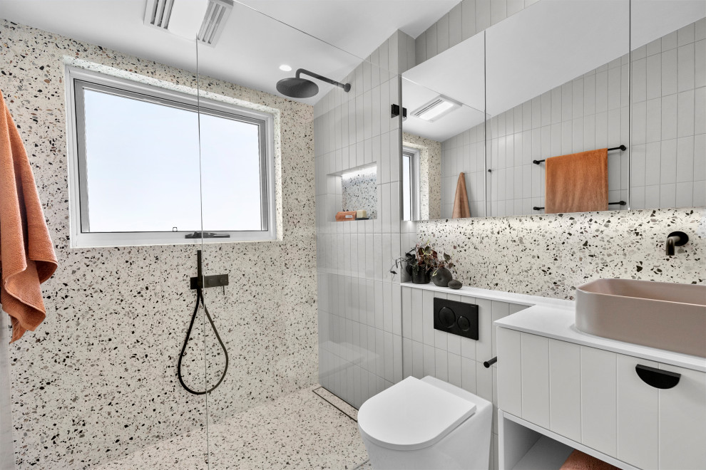 Свежая идея для дизайна: главная ванная комната среднего размера в стиле модернизм с белыми фасадами, душевой комнатой, унитазом-моноблоком, разноцветной плиткой, плиткой кабанчик, разноцветными стенами, полом из терраццо, настольной раковиной, столешницей из искусственного камня, разноцветным полом, открытым душем, белой столешницей, нишей, тумбой под одну раковину, встроенной тумбой и сводчатым потолком - отличное фото интерьера