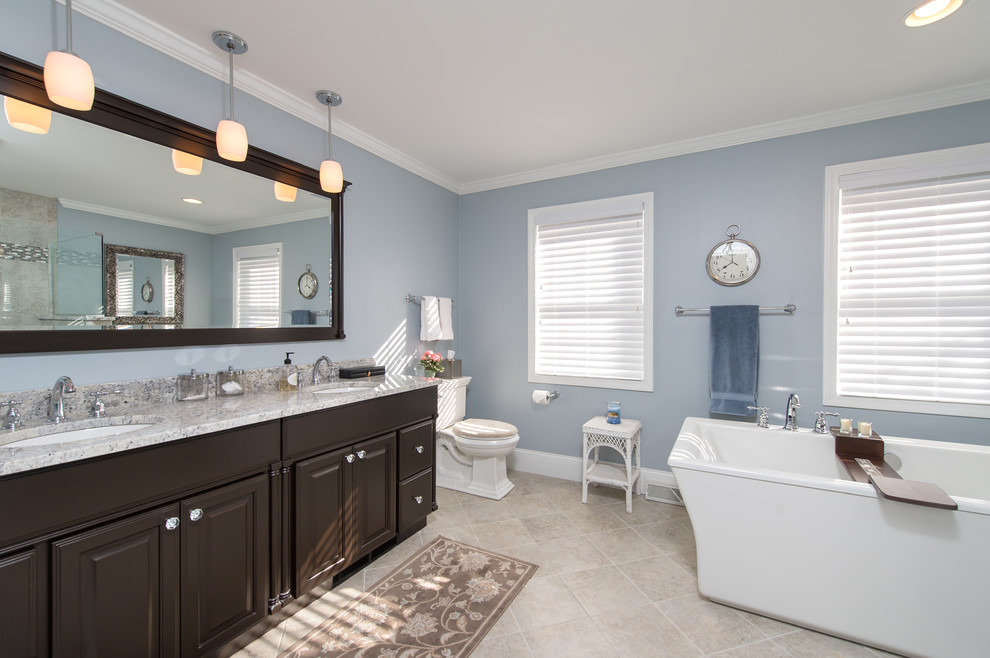 Photo of a large traditional master bathroom in Boston with an undermount sink, dark wood cabinets, granite benchtops, a freestanding tub, an open shower, a two-piece toilet, multi-coloured tile, porcelain tile, blue walls, porcelain floors and raised-panel cabinets.
