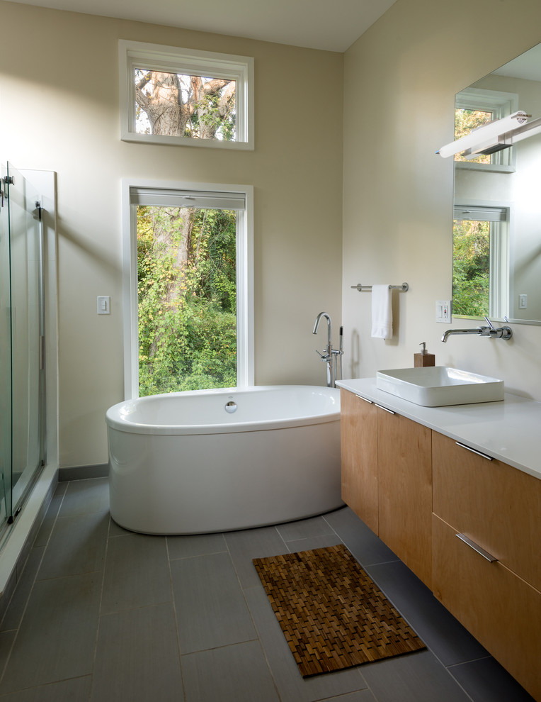 Photo of a mid-sized contemporary master bathroom in DC Metro with flat-panel cabinets, brown cabinets, a freestanding tub, beige walls, porcelain floors, a vessel sink, engineered quartz benchtops, grey floor, a sliding shower screen and white benchtops.