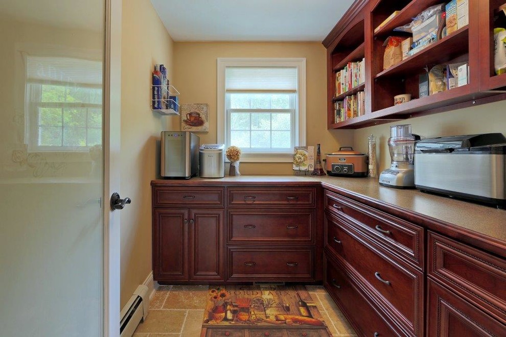 Inspiration for a mid-sized mediterranean l-shaped kitchen pantry in Boston with recessed-panel cabinets, dark wood cabinets, laminate benchtops, stainless steel appliances and travertine floors.