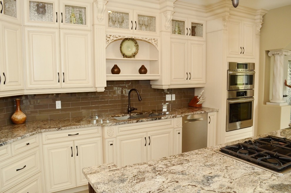 Large traditional l-shaped kitchen in Toronto with an undermount sink, raised-panel cabinets, white cabinets, granite benchtops, brown splashback, glass tile splashback, stainless steel appliances, marble floors and with island.