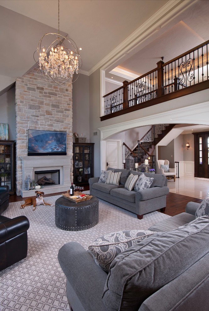 Inspiration for a transitional open concept family room in Other with grey walls, dark hardwood floors, a standard fireplace, a stone fireplace surround, a wall-mounted tv and brown floor.