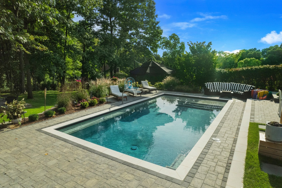 Imagen de piscina tradicional grande rectangular en patio trasero con paisajismo de piscina y adoquines de piedra natural