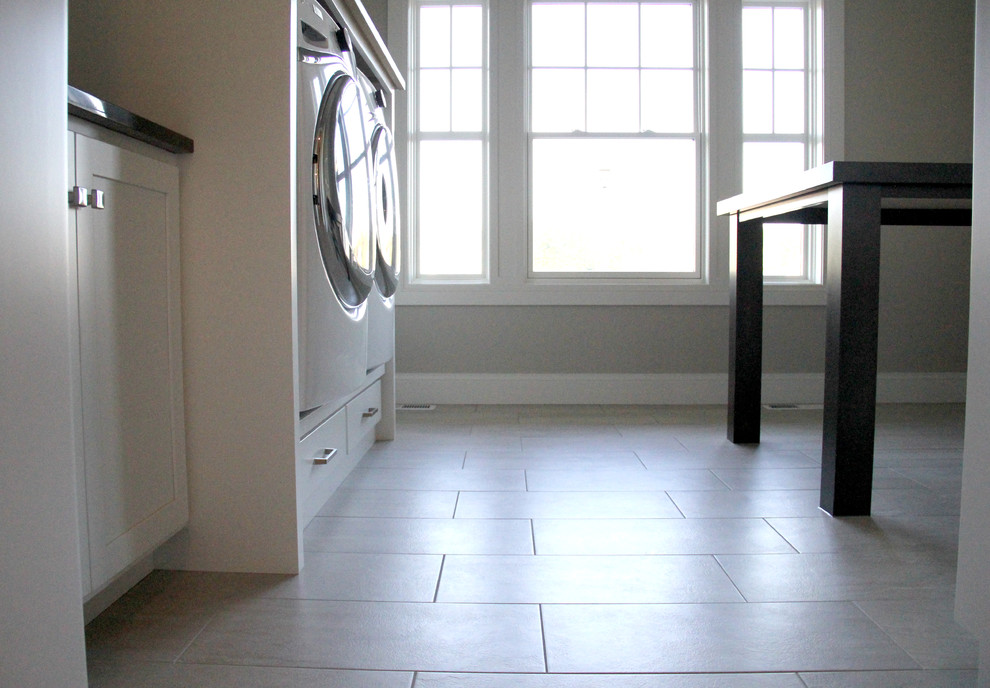Mid-sized single-wall ceramic tile and beige floor dedicated laundry room photo with recessed-panel cabinets, white cabinets, granite countertops, gray walls and a side-by-side washer/dryer