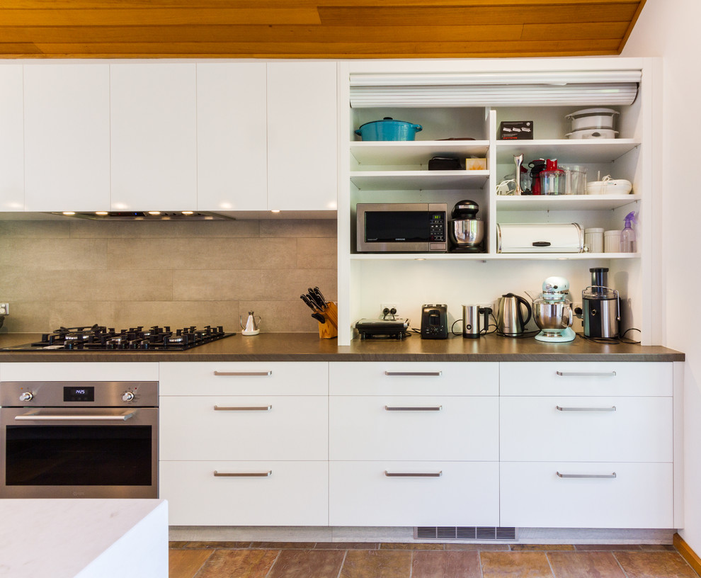Inspiration for a large midcentury galley eat-in kitchen in Melbourne with a drop-in sink, flat-panel cabinets, white cabinets, quartz benchtops, beige splashback, subway tile splashback, stainless steel appliances, porcelain floors, with island, brown floor and grey benchtop.
