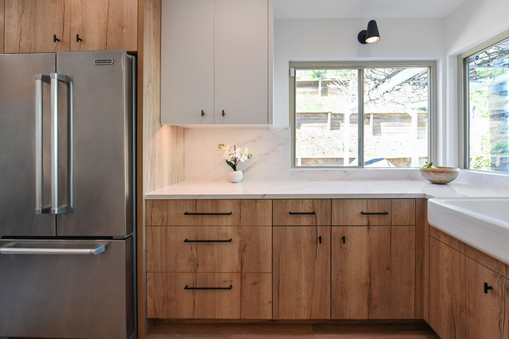 Photo of a mid-sized country l-shaped eat-in kitchen in Austin with a farmhouse sink, flat-panel cabinets, medium wood cabinets, wood benchtops, white splashback, marble splashback, stainless steel appliances, medium hardwood floors, brown floor and brown benchtop.