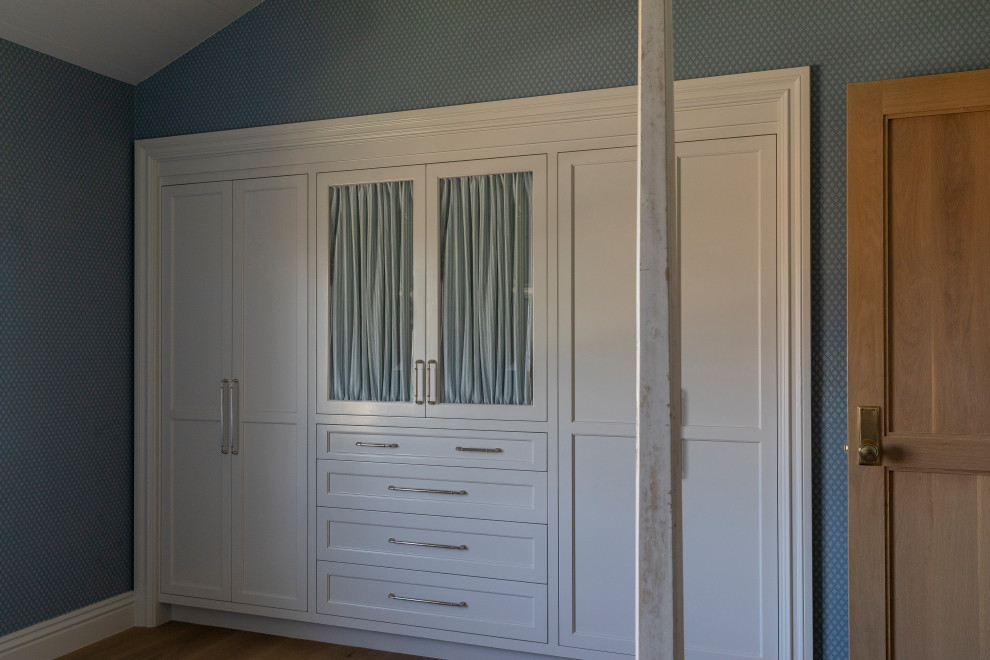 Beach style gender-neutral medium tone wood floor, brown floor and vaulted ceiling built-in closet photo in Orange County with beige cabinets