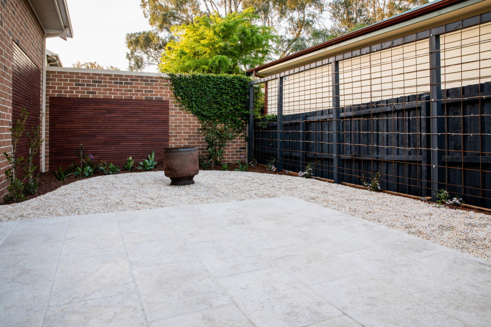Inspiration for a mid-sized contemporary backyard partial sun garden for spring in Melbourne with natural stone pavers.