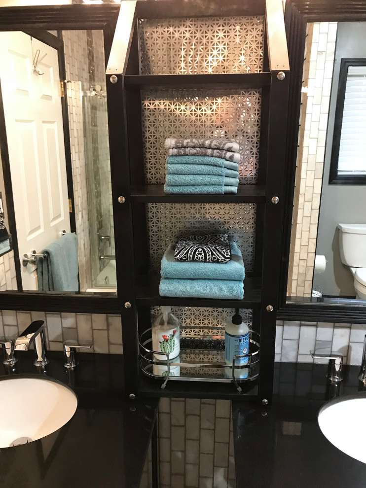 Mid-sized modern bathroom in Albuquerque with glass-front cabinets, black cabinets, a shower/bathtub combo, a two-piece toilet, black and white tile, marble, grey walls, porcelain floors, an undermount sink, granite benchtops, grey floor, a sliding shower screen and black benchtops.
