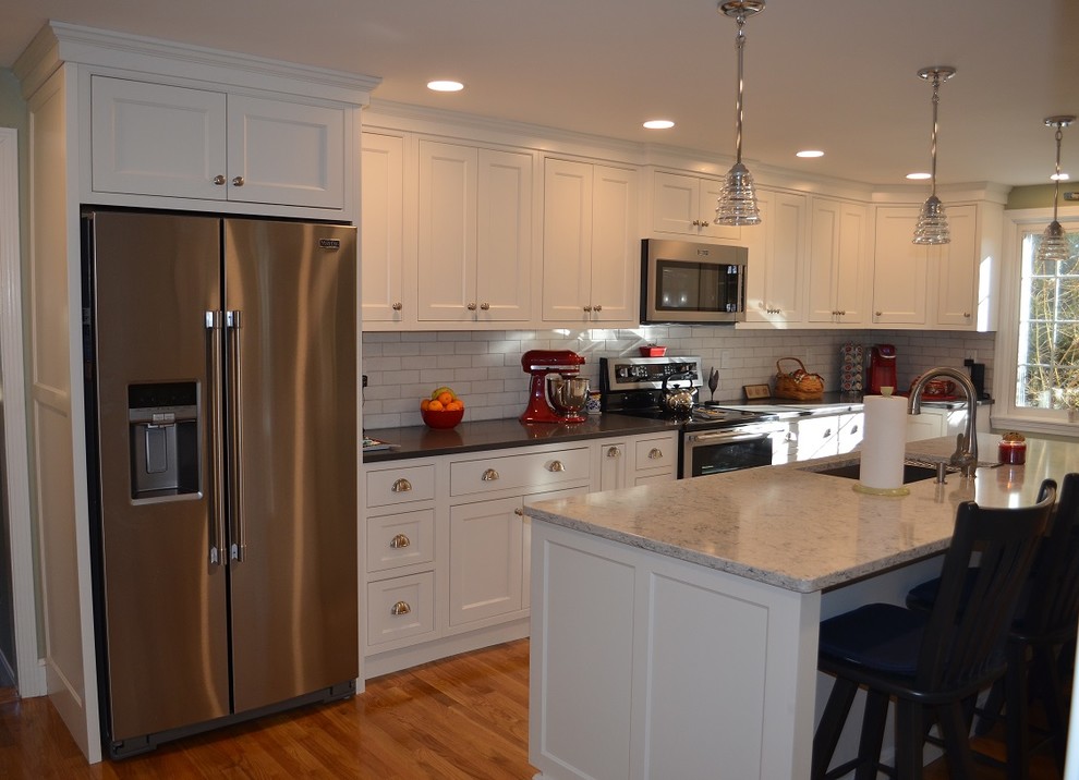 Transitional l-shaped light wood floor eat-in kitchen photo in Boston with an undermount sink, beaded inset cabinets, white cabinets, quartz countertops, white backsplash, ceramic backsplash, stainless steel appliances, an island and gray countertops