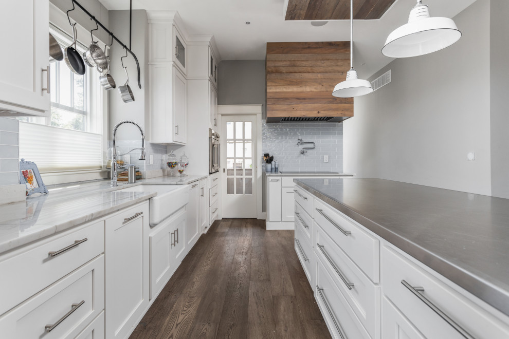 Inspiration for a country kitchen in Indianapolis with shaker cabinets, white cabinets, quartzite benchtops, blue splashback, glass tile splashback, stainless steel appliances, medium hardwood floors, with island, brown floor and multi-coloured benchtop.
