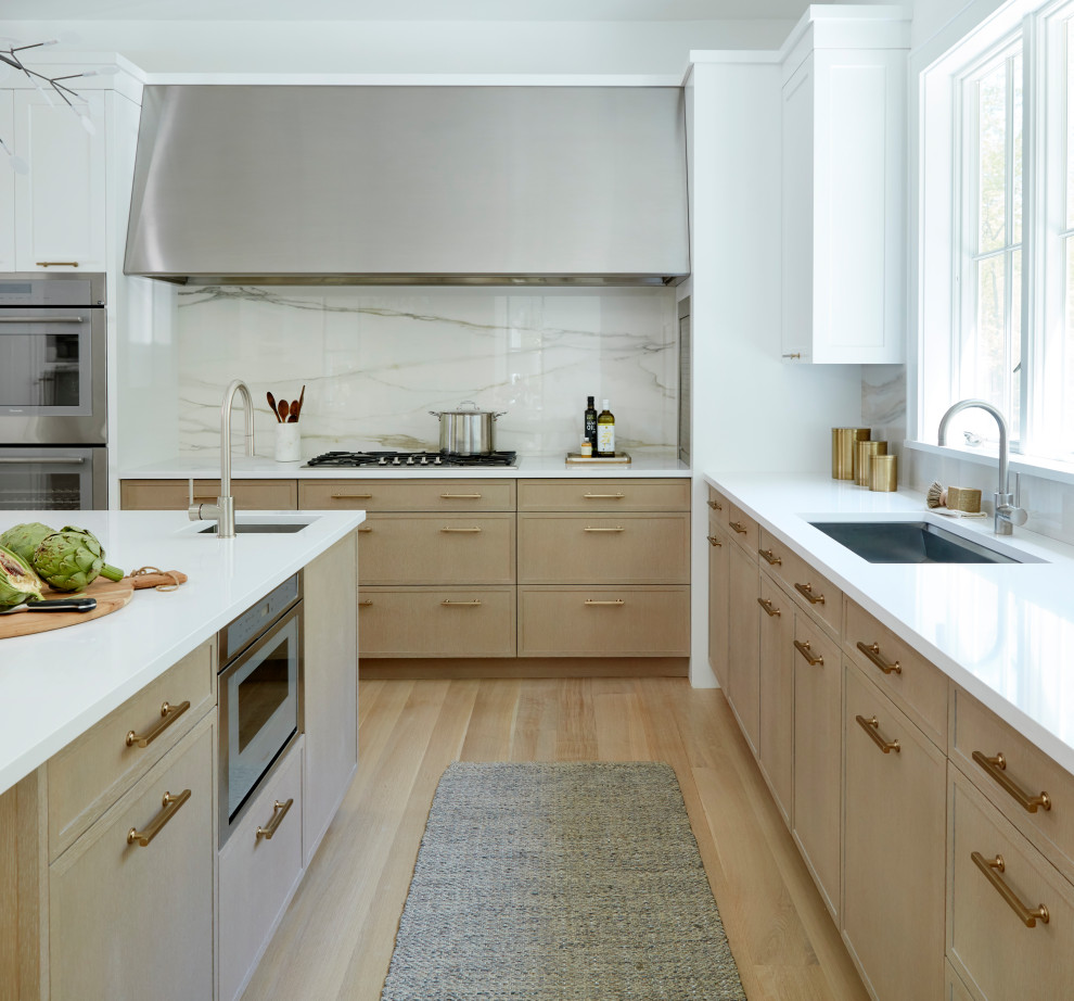 Design ideas for a large u-shaped open plan kitchen in New York with flat-panel cabinets, white cabinets, quartzite benchtops, white splashback, porcelain splashback, stainless steel appliances, light hardwood floors, with island, brown floor and white benchtop.