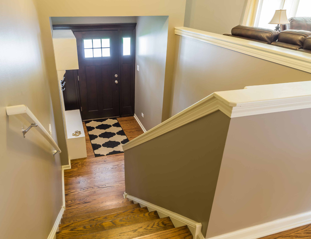 This is an example of a mid-sized transitional wood straight staircase in Chicago with wood risers, mixed railing and wallpaper.