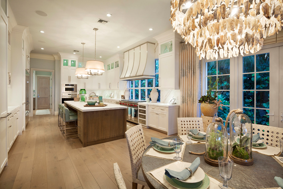 Design ideas for an expansive transitional l-shaped open plan kitchen in Miami with shaker cabinets, white cabinets, marble benchtops, white splashback, light hardwood floors and with island.