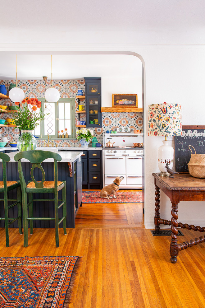 Inspiration for an eclectic galley eat-in kitchen in Los Angeles with a farmhouse sink, shaker cabinets, blue cabinets, marble benchtops, multi-coloured splashback, porcelain splashback, white appliances, medium hardwood floors, with island and white benchtop.