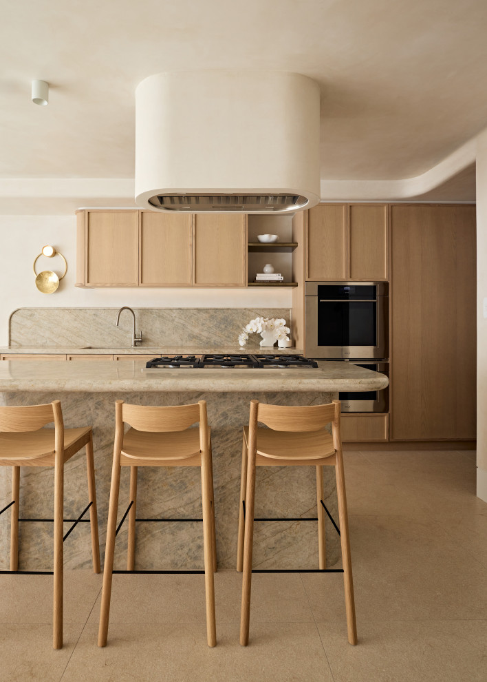 Inspiration for a beach style galley kitchen in Sydney with an undermount sink, shaker cabinets, light wood cabinets, beige splashback, stone slab splashback, stainless steel appliances, with island, beige floor and beige benchtop.