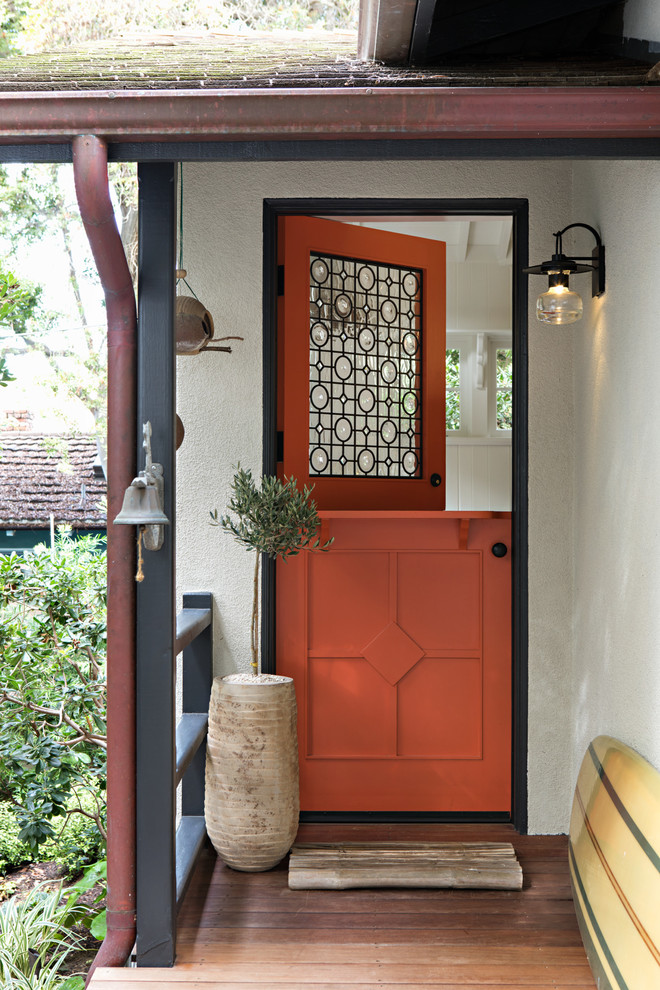 This is an example of a beach style front door in Orange County with a dutch front door and an orange front door.