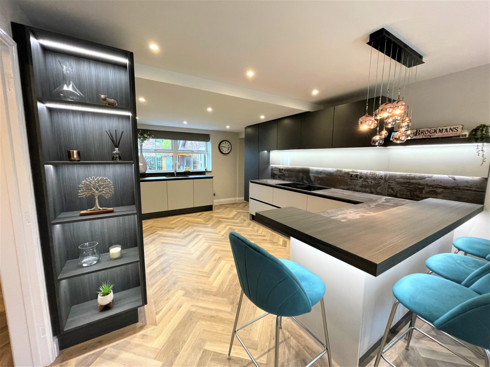 Photo of a medium sized contemporary l-shaped kitchen/diner in Other with a single-bowl sink, flat-panel cabinets, dark wood cabinets, engineered stone countertops, black appliances, vinyl flooring and feature lighting.
