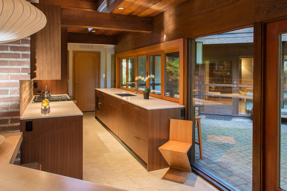 This is an example of a mid-sized midcentury galley eat-in kitchen in Vancouver with an undermount sink, flat-panel cabinets, medium wood cabinets, quartz benchtops, white benchtop, concrete floors, grey floor, brown splashback, brick splashback, stainless steel appliances and no island.