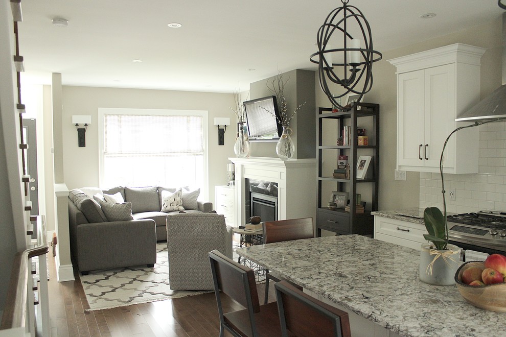 Photo of a small transitional open concept living room in Toronto with grey walls, medium hardwood floors, a standard fireplace, a stone fireplace surround and a wall-mounted tv.