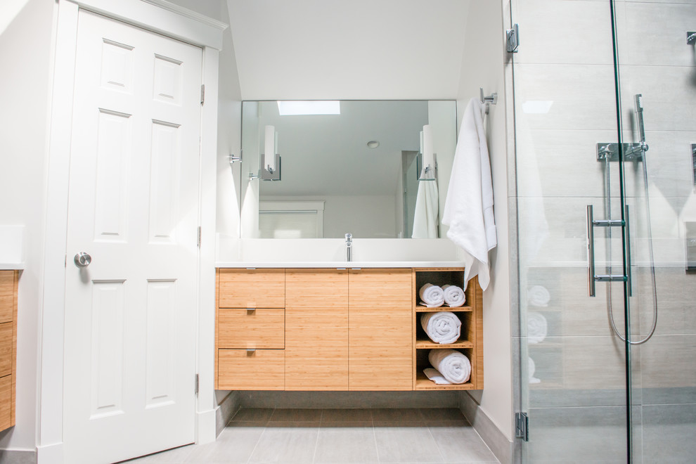 This is an example of a large transitional master bathroom in Portland Maine with flat-panel cabinets, light wood cabinets, a corner tub, an alcove shower, a two-piece toilet, white tile, white walls, ceramic floors and an undermount sink.