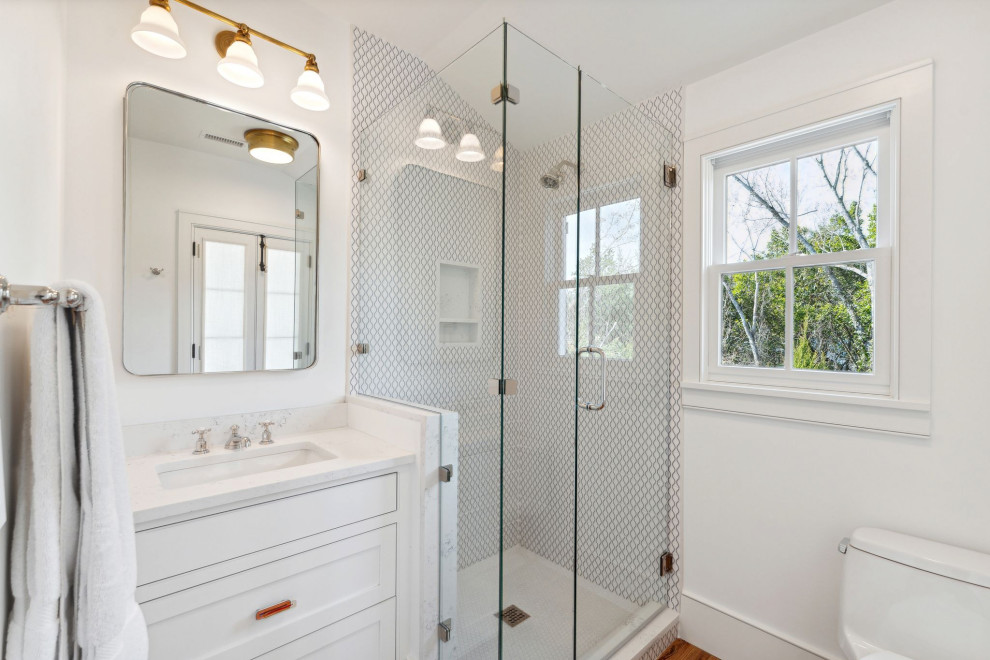 Historic Sea Cabins - Guest bathroom featuring original heart pine floors, custom inset vanity, penny round tile shower floor, patterned ceramic tile walls, quartz countertops and mixed metal fixtures.
