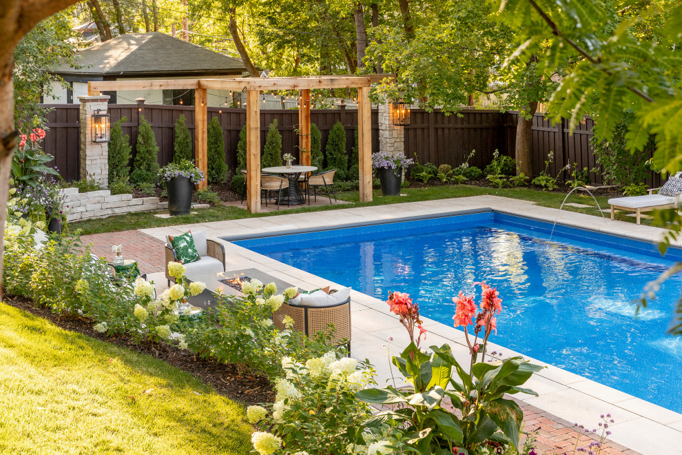 Modelo de piscina natural de estilo americano grande rectangular en patio trasero con paisajismo de piscina y adoquines de piedra natural