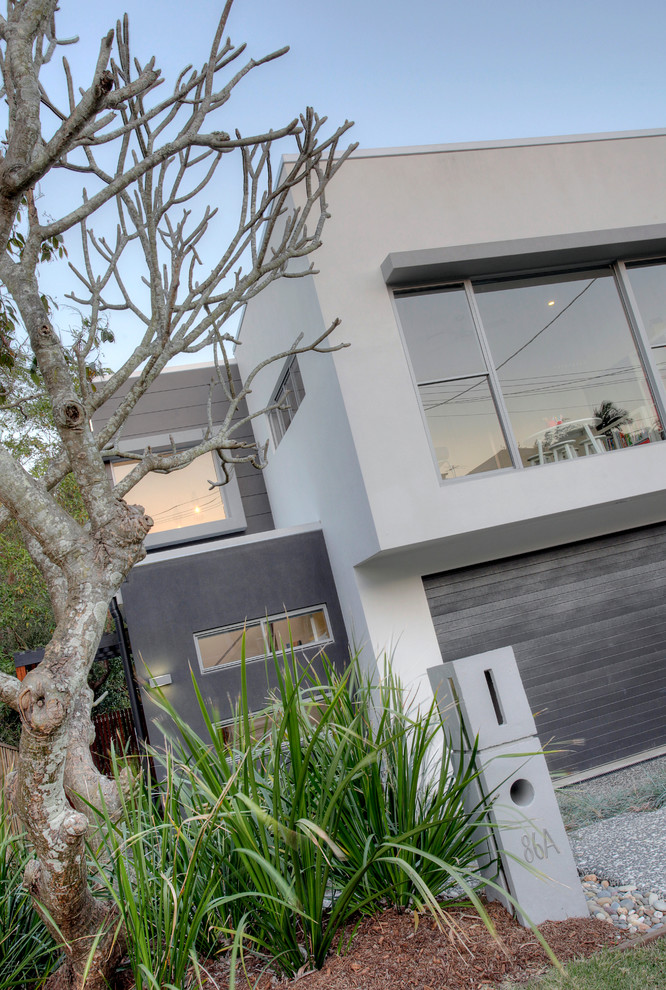 This is an example of a mid-sized contemporary two-storey grey exterior in Brisbane with mixed siding and a flat roof.