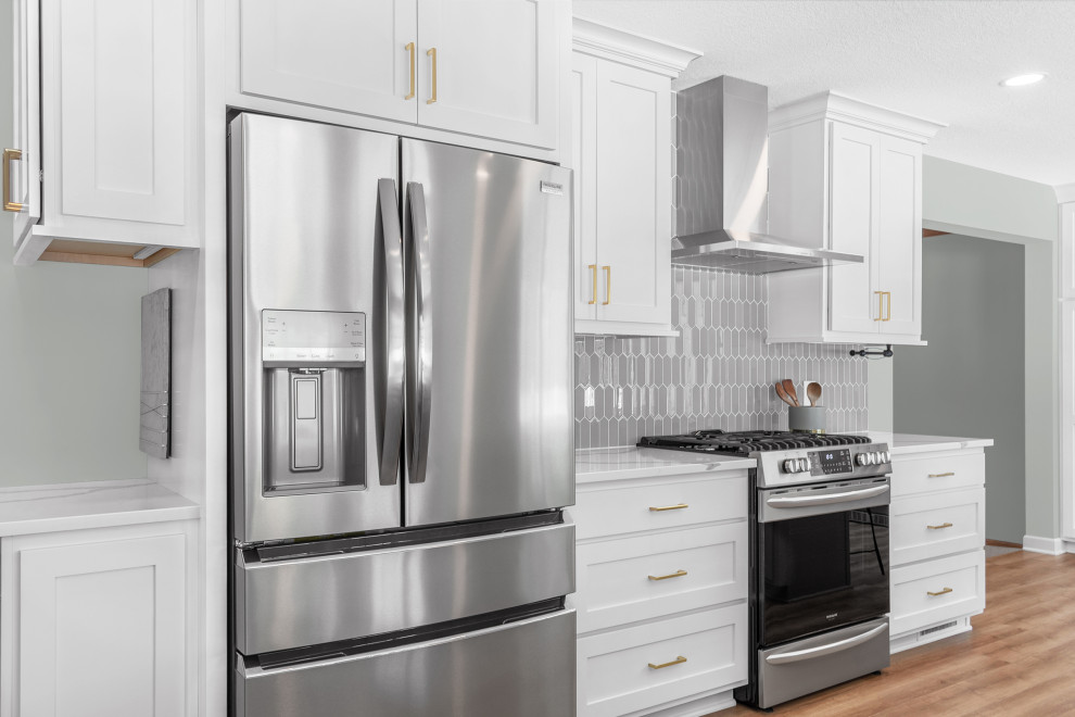 Example of a mid-sized transitional l-shaped light wood floor and brown floor eat-in kitchen design in Minneapolis with an undermount sink, recessed-panel cabinets, gray cabinets, quartz countertops, gray backsplash, glass tile backsplash, stainless steel appliances, an island and white countertops