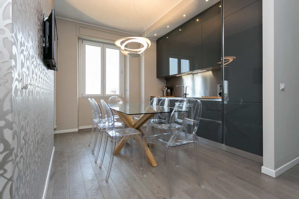Photo of a small contemporary single-wall eat-in kitchen in Milan with an integrated sink, flat-panel cabinets, black cabinets, metallic splashback, metal splashback, stainless steel appliances and no island.