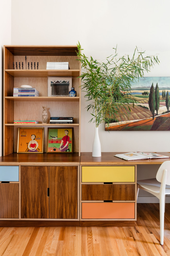 Small midcentury home office in Seattle with beige walls, light hardwood floors and a built-in desk.