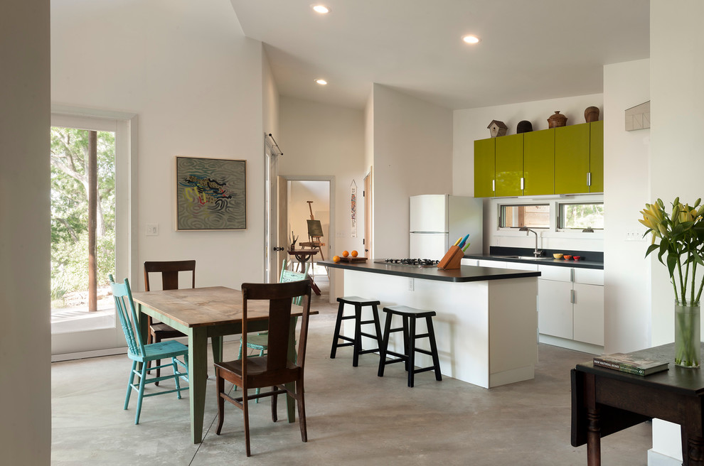 Inspiration for a small contemporary galley concrete floor eat-in kitchen remodel in DC Metro with a drop-in sink, flat-panel cabinets, green cabinets, white appliances, laminate countertops, white backsplash and an island
