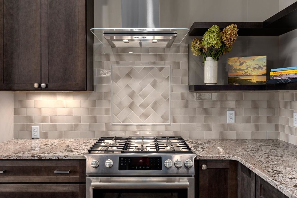 Mid-sized mountain style l-shaped light wood floor eat-in kitchen photo with an undermount sink, recessed-panel cabinets, dark wood cabinets, granite countertops, gray backsplash, ceramic backsplash, stainless steel appliances and an island