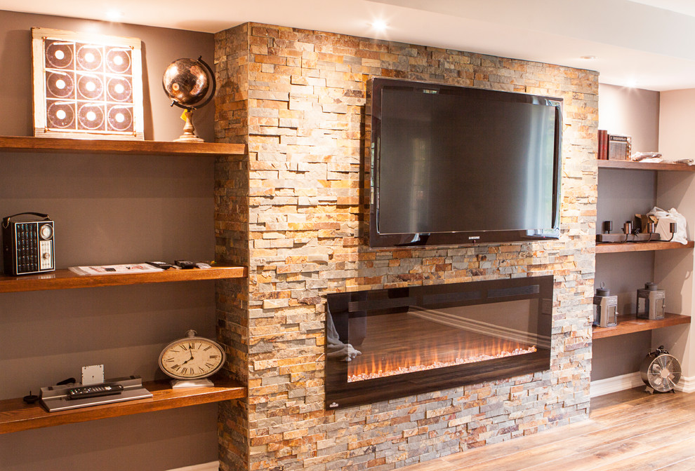 Inspiration for a large country walk-out basement in Toronto with grey walls, laminate floors, a standard fireplace, a stone fireplace surround and brown floor.