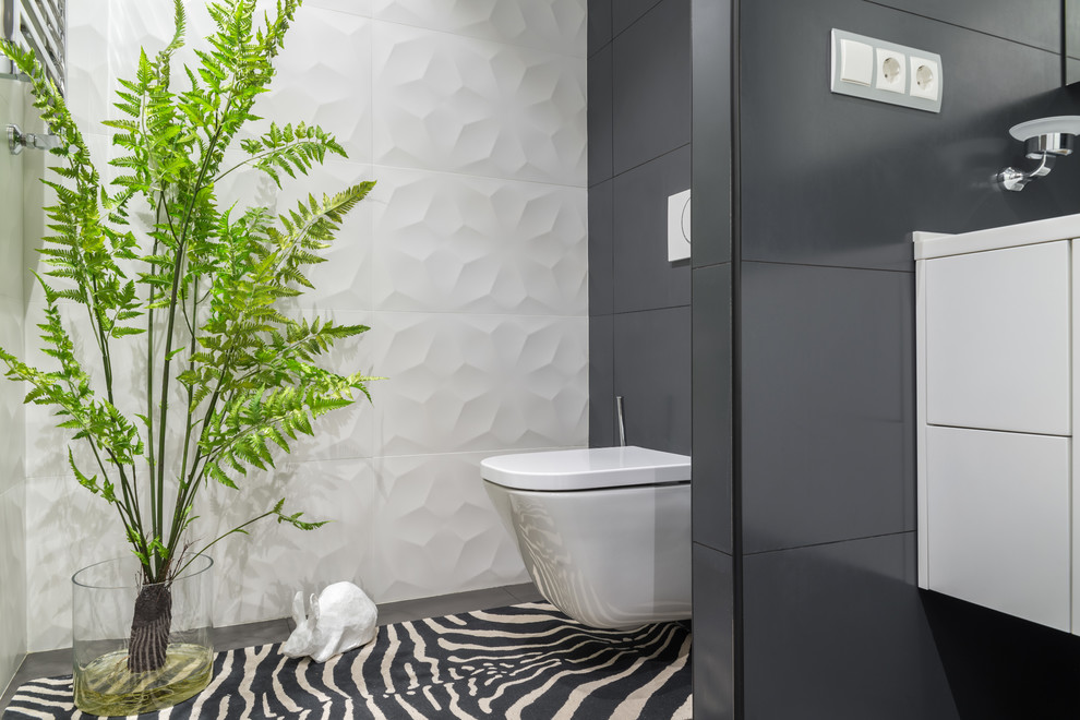 This is an example of a contemporary powder room in Moscow with flat-panel cabinets, white cabinets, a wall-mount toilet, white tile, gray tile, black floor and white benchtops.