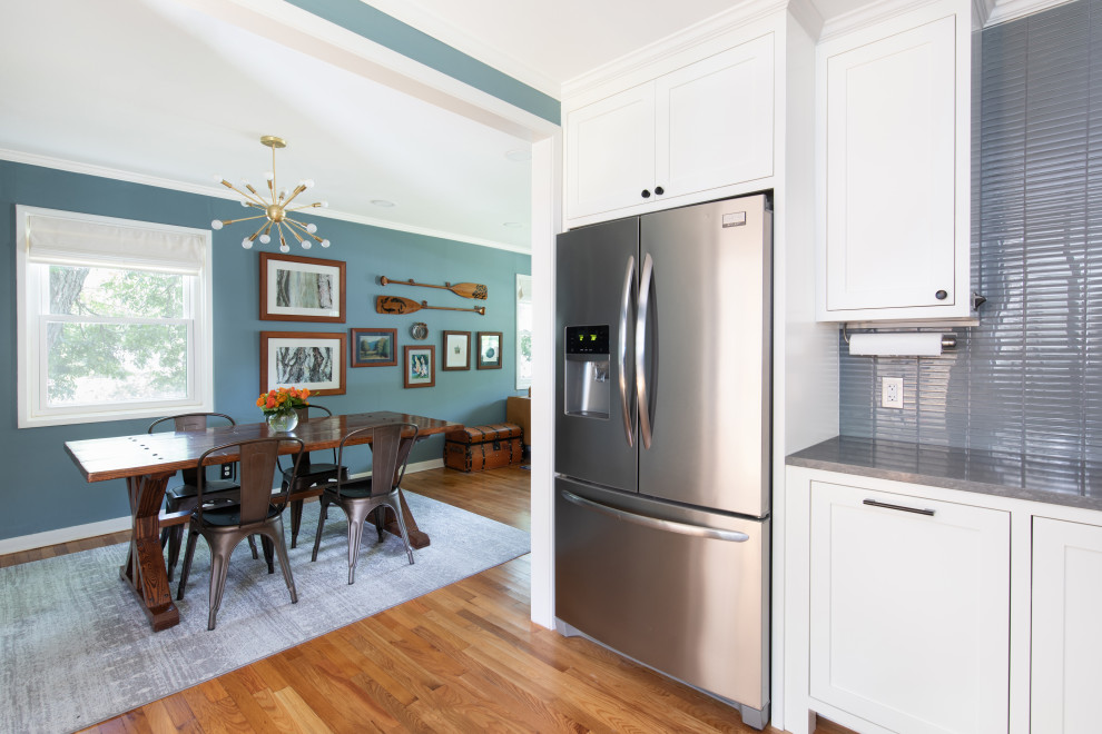 Bild på ett mellanstort vintage grå grått kök, med en undermonterad diskho, skåp i shakerstil, vita skåp, bänkskiva i kvarts, blått stänkskydd, stänkskydd i glaskakel, rostfria vitvaror, ljust trägolv och brunt golv