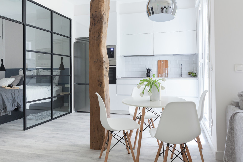 Small scandinavian single-wall eat-in kitchen in Madrid with flat-panel cabinets, white cabinets, white splashback, subway tile splashback, no island, an undermount sink, stainless steel appliances, laminate floors, grey floor and white benchtop.