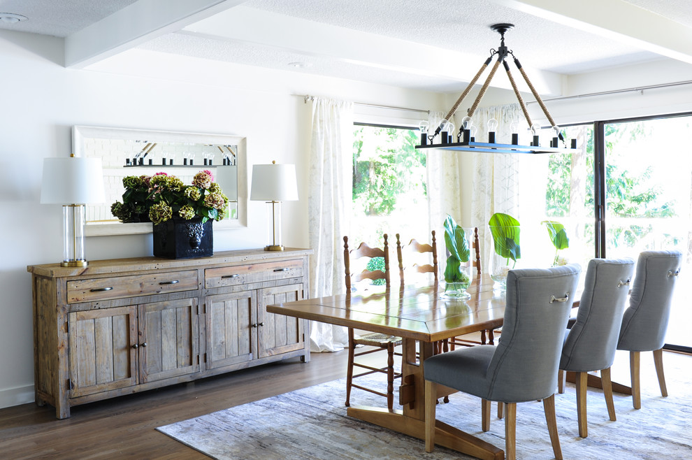 Inspiration for a large beach style kitchen/dining combo in Vancouver with white walls, medium hardwood floors, a two-sided fireplace, a brick fireplace surround, brown floor and exposed beam.